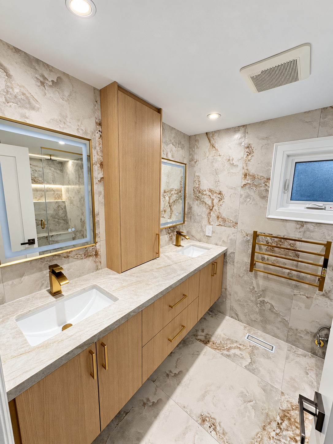 Custom double vanity with warm wood cabinetry, stone counter and brushed-gold faucets