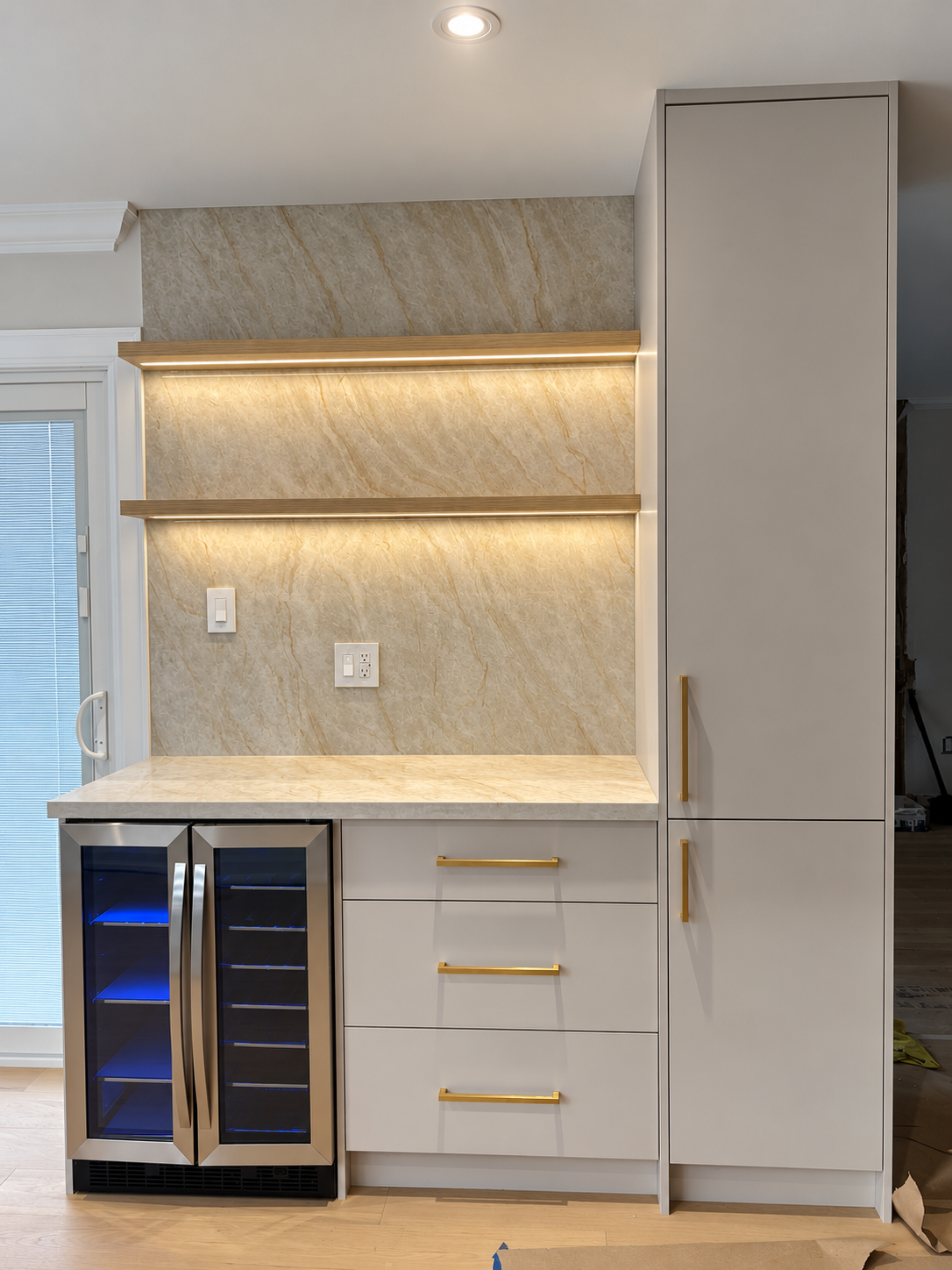 Custom beverage station with illuminated stone backsplash and brushed-gold hardware